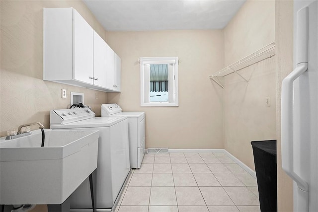 laundry room featuring sink, light tile patterned flooring, cabinets, and independent washer and dryer