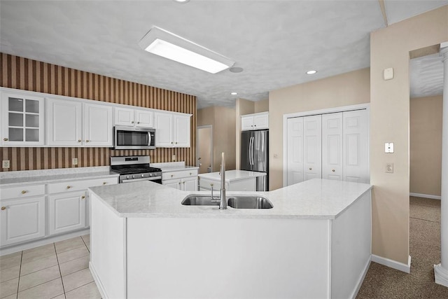 kitchen with sink, stainless steel appliances, white cabinetry, and a center island with sink