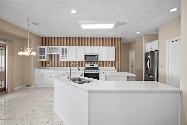 kitchen featuring pendant lighting, white cabinets, stainless steel appliances, an island with sink, and sink