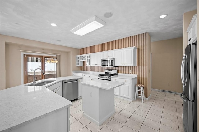 kitchen with appliances with stainless steel finishes, sink, decorative light fixtures, white cabinets, and a center island