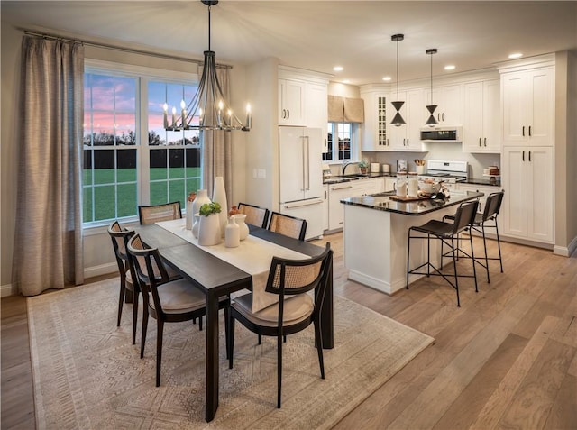 dining area featuring sink, light hardwood / wood-style flooring, and an inviting chandelier