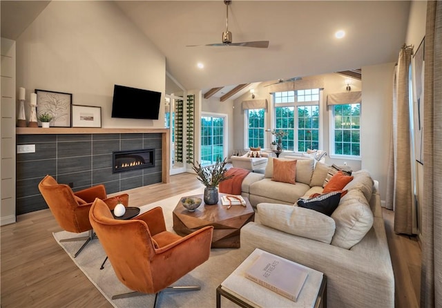 living room with ceiling fan, light hardwood / wood-style flooring, high vaulted ceiling, and a fireplace