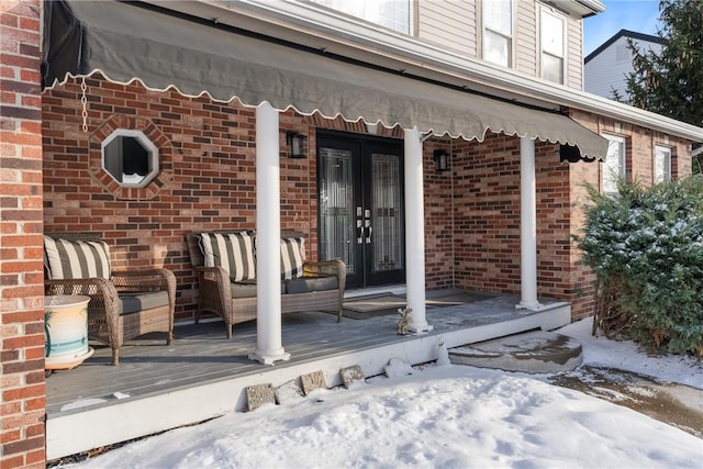 snow covered property entrance with a wooden deck, outdoor lounge area, and french doors