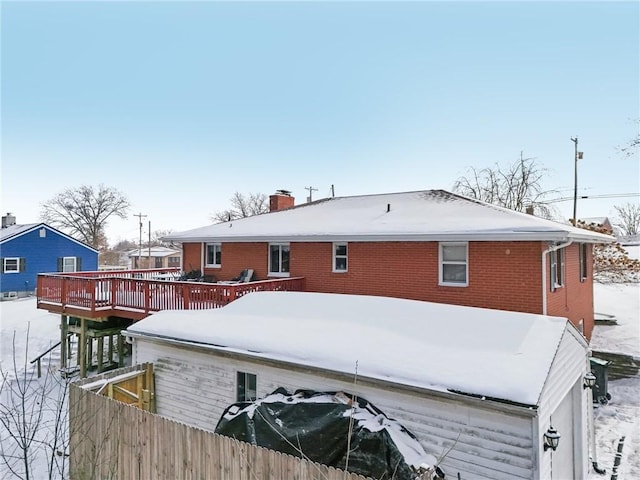 snow covered house featuring a wooden deck