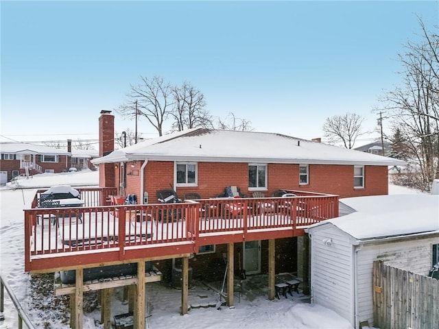 snow covered back of property featuring a deck