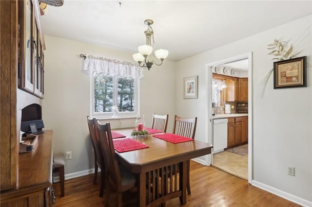 dining room featuring sink, light hardwood / wood-style flooring, and an inviting chandelier