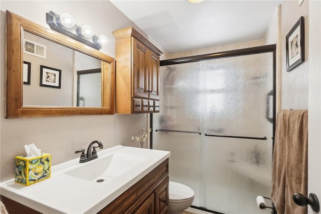 bathroom with vanity, toilet, and a shower with shower door