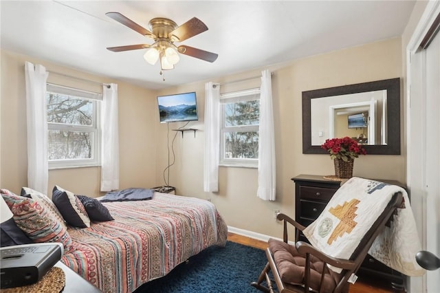 bedroom featuring ceiling fan, multiple windows, and wood-type flooring