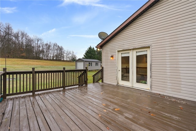 deck with a garage, an outbuilding, and a lawn