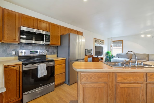 kitchen featuring decorative backsplash, sink, light hardwood / wood-style flooring, and stainless steel appliances