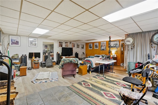 interior space featuring light hardwood / wood-style flooring, wooden walls, and a drop ceiling