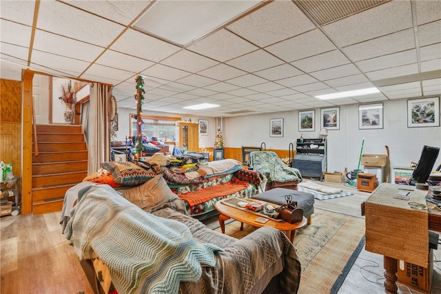 living room featuring light wood-type flooring and a paneled ceiling