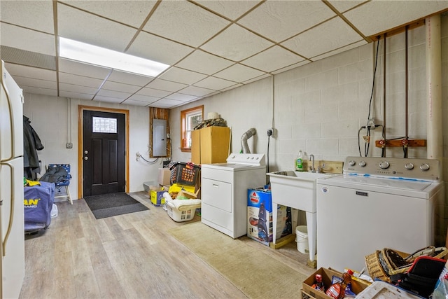 laundry area with electric panel, light hardwood / wood-style flooring, and washer and dryer