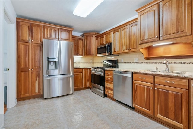 kitchen featuring sink, stainless steel appliances, light stone counters, and tasteful backsplash