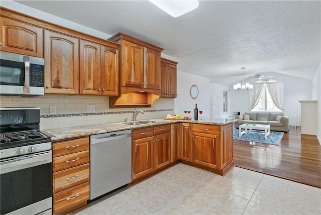 kitchen featuring light stone countertops, appliances with stainless steel finishes, sink, an inviting chandelier, and backsplash