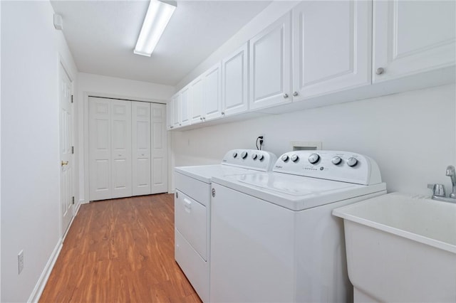 washroom featuring sink, hardwood / wood-style floors, cabinets, and washing machine and clothes dryer