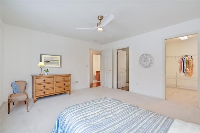 bedroom with light colored carpet, a closet, ceiling fan, and a walk in closet