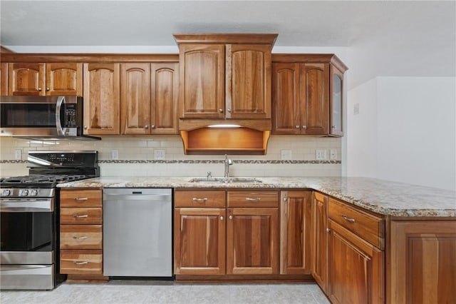 kitchen with light tile patterned floors, decorative backsplash, sink, stainless steel appliances, and light stone counters