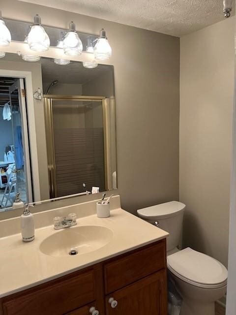 bathroom featuring an enclosed shower, vanity, toilet, and a textured ceiling