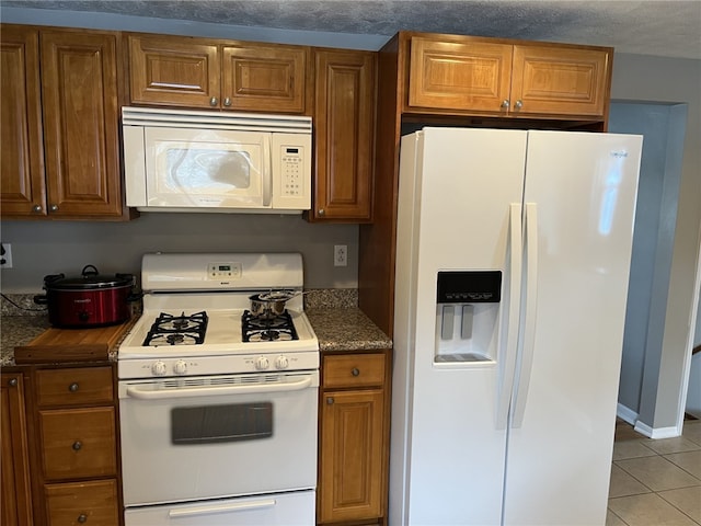 kitchen featuring white appliances, a textured ceiling, and light tile patterned flooring