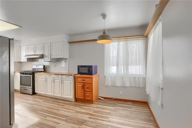 kitchen featuring white cabinetry, hanging light fixtures, decorative backsplash, light wood-type flooring, and stainless steel appliances