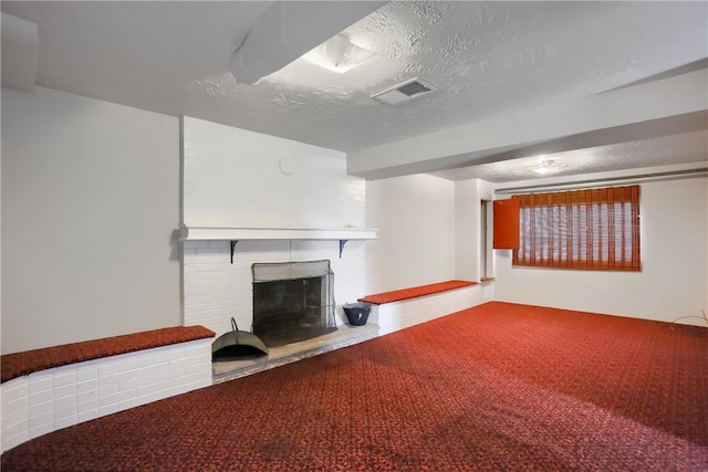 basement featuring a brick fireplace, a textured ceiling, and carpet flooring