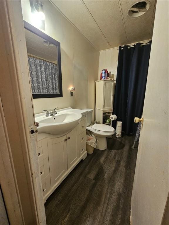 bathroom featuring a textured ceiling, hardwood / wood-style flooring, toilet, and vanity