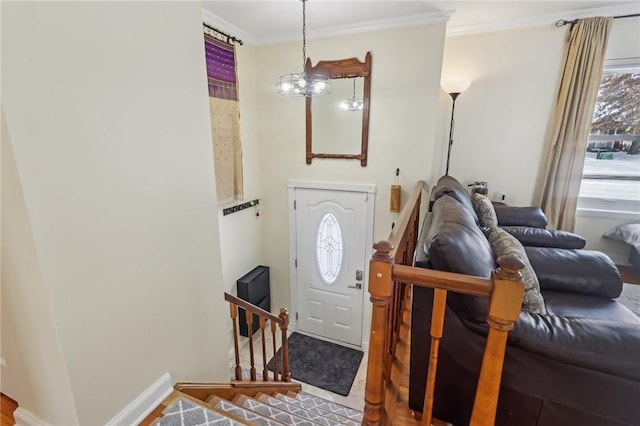 foyer entrance with crown molding and a chandelier