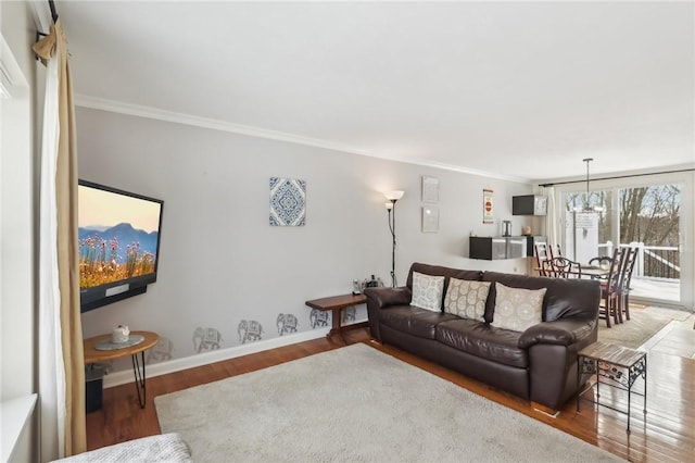 living room featuring wood-type flooring, a chandelier, and crown molding