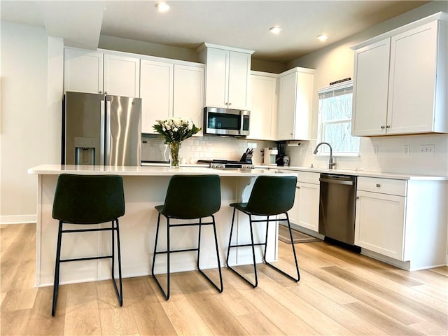 kitchen with stainless steel appliances, a center island, white cabinets, and decorative backsplash