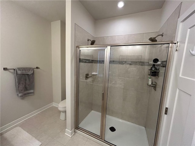 bathroom featuring toilet, a shower with shower door, and tile patterned flooring