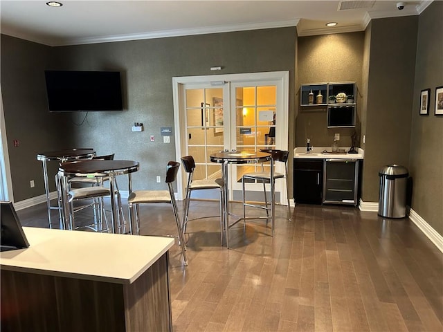 bar featuring hardwood / wood-style floors, ornamental molding, and sink