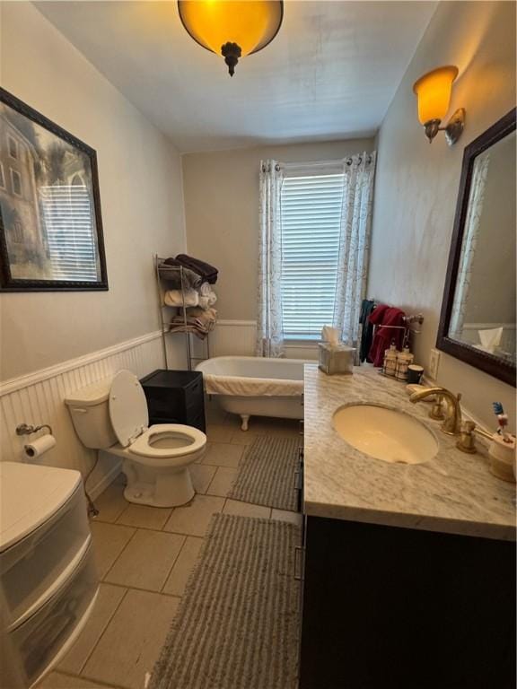 bathroom with a tub to relax in, toilet, tile patterned floors, and vanity