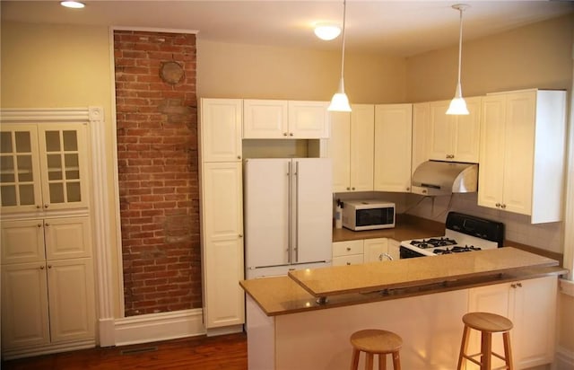 kitchen with white appliances, white cabinetry, kitchen peninsula, pendant lighting, and a breakfast bar area