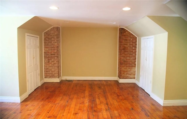 additional living space with hardwood / wood-style flooring and lofted ceiling