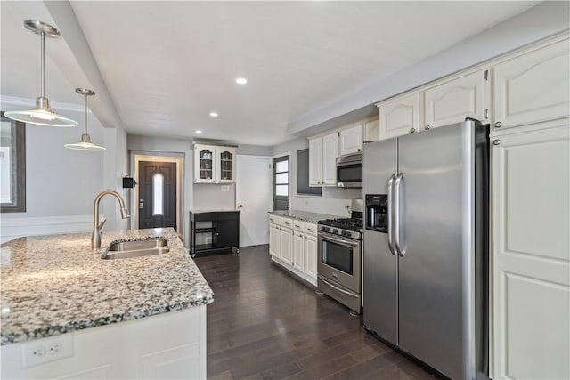 kitchen featuring decorative light fixtures, white cabinetry, sink, light stone counters, and stainless steel appliances