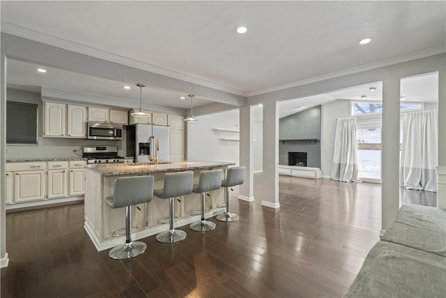 kitchen featuring hanging light fixtures, stainless steel appliances, light stone countertops, and a kitchen island