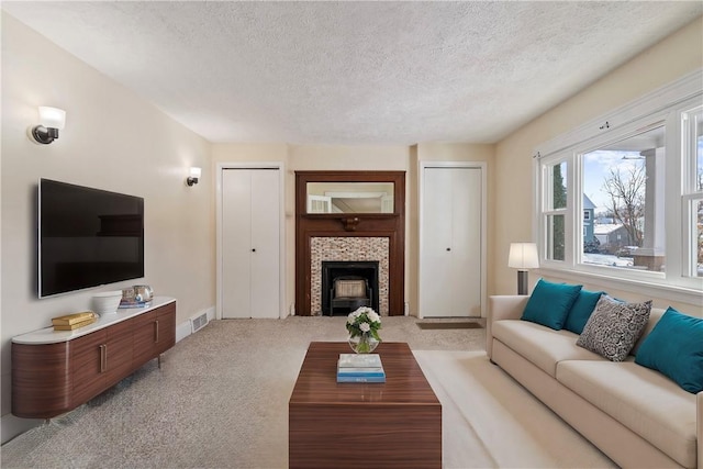 living room featuring light colored carpet, a fireplace, and a textured ceiling