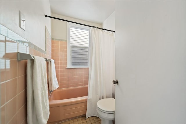 bathroom with shower / bath combo, toilet, tile patterned flooring, and tile walls