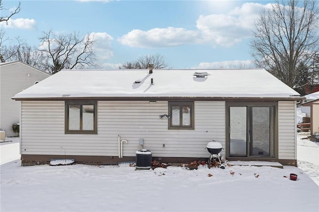 snow covered back of property featuring cooling unit