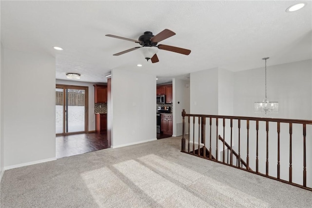 carpeted spare room with ceiling fan with notable chandelier