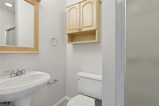 bathroom featuring sink, toilet, and a shower with door