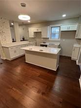 kitchen with decorative light fixtures, white cabinets, a center island, and dark wood-type flooring