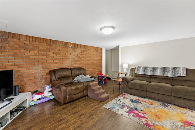 living room featuring dark wood-type flooring and brick wall