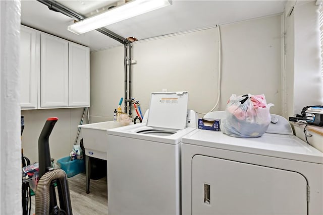 washroom with light wood-type flooring, separate washer and dryer, and cabinets