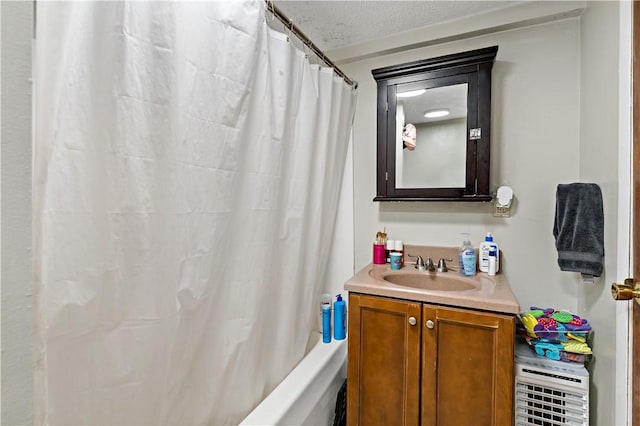 bathroom featuring vanity, shower / bath combo with shower curtain, and a textured ceiling