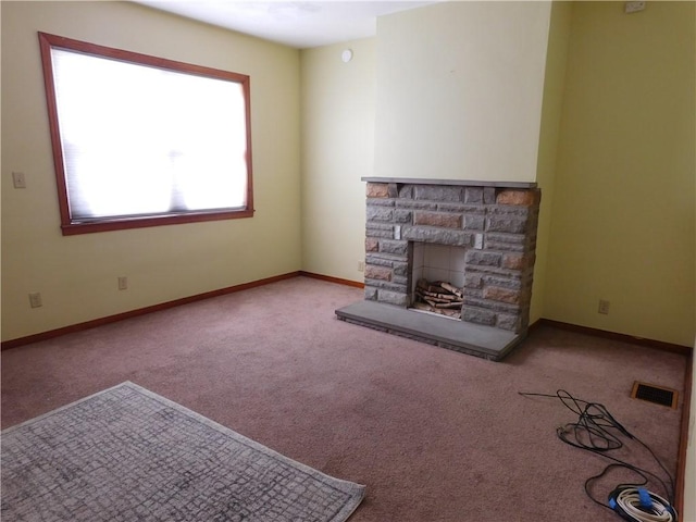 unfurnished living room featuring a stone fireplace and light colored carpet