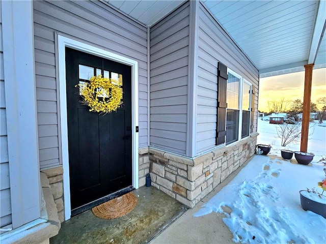 snow covered property entrance with a porch