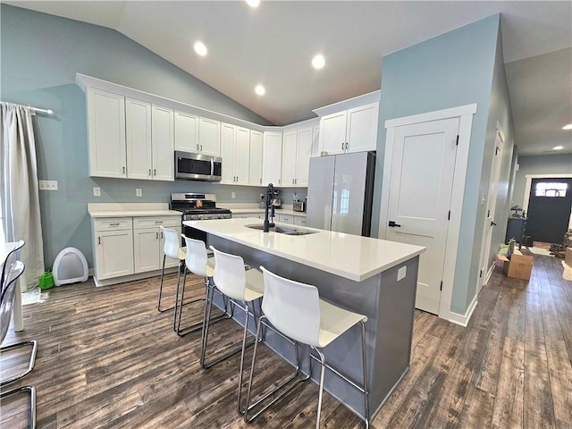 kitchen featuring white cabinetry, stainless steel appliances, an island with sink, sink, and vaulted ceiling