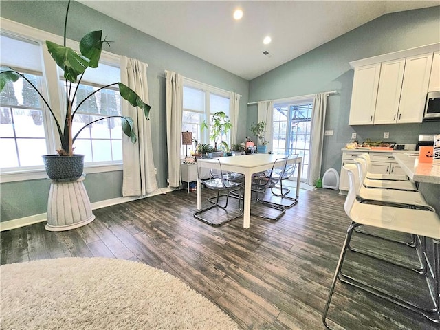 dining room with dark wood-type flooring, a healthy amount of sunlight, and lofted ceiling